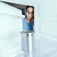 A Generic Can of Food in an Otherwise Empty Freezer With a Girl Looking in Dubiously