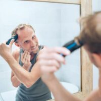 Man Using Beard Trimmer on Top of His Head and Smiling