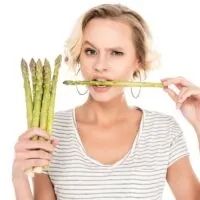 A Woman Holding Up Asparagus and Biting It