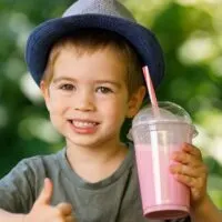 Young Boy Holding a Milshake and Smiling