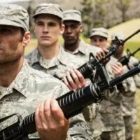 Group of both younger and older military soldiers standing with rifles at boot camp