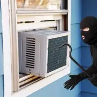 Old-air-conditioner-installed-on-house-window-and-a-burglar-with-mask-and-crowbar