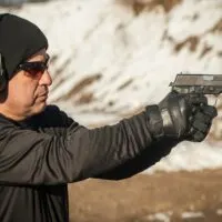 Closeup shot of man holding a handgun with shooting gloves