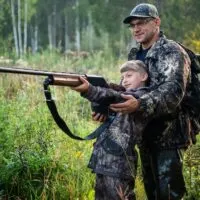 Father teaching son to use a shotgun