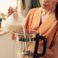 Woman Pouring Milk Into a Blender to Make a Milkshake or Smoothie