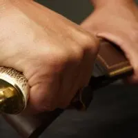 Hand pulling a blade out of a sheath or a scabbard