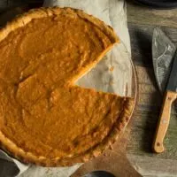 Homemade Sweet Potato Pie on a Table With a Piece Missing an a Knife Nearby