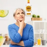 Woman thinking in kitchen with bottle of gin over head