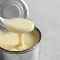 Open can of evaporated milk or milnot with a spoon