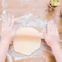 A woman rolling dough to make homemade empanadas