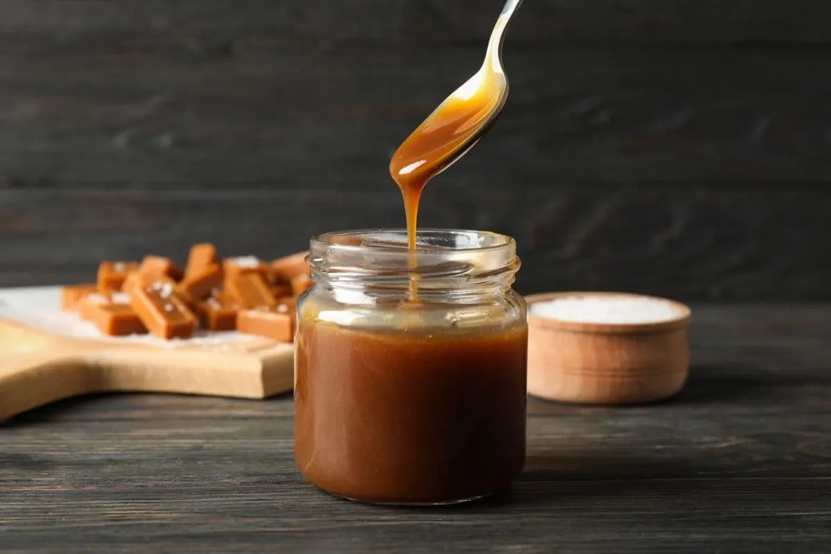 A jar of caramel extract with a spoon
